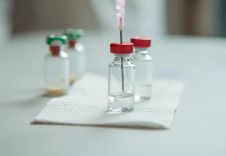 Vaccine bottles and syringe for injection on a gray ambulance table selective focus