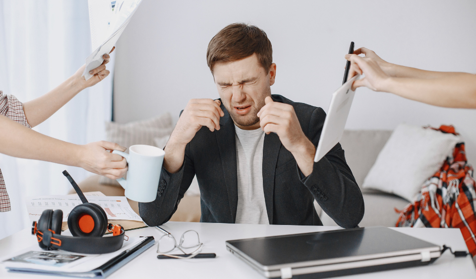 Overwhelmed adult multitasking at a cluttered desk, a common sign of adult ADHD