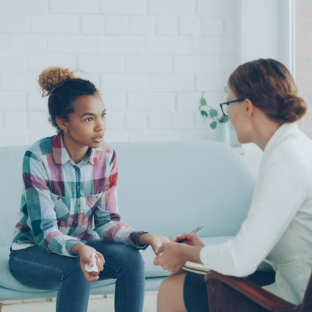 A young woman talks with a mental health provider during a calm, seated conversation about anxiety symptoms.
