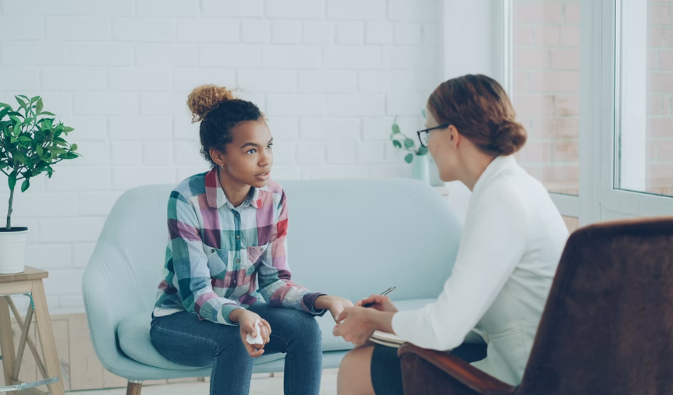 A young woman talks with a mental health provider during a calm, seated conversation about anxiety symptoms.