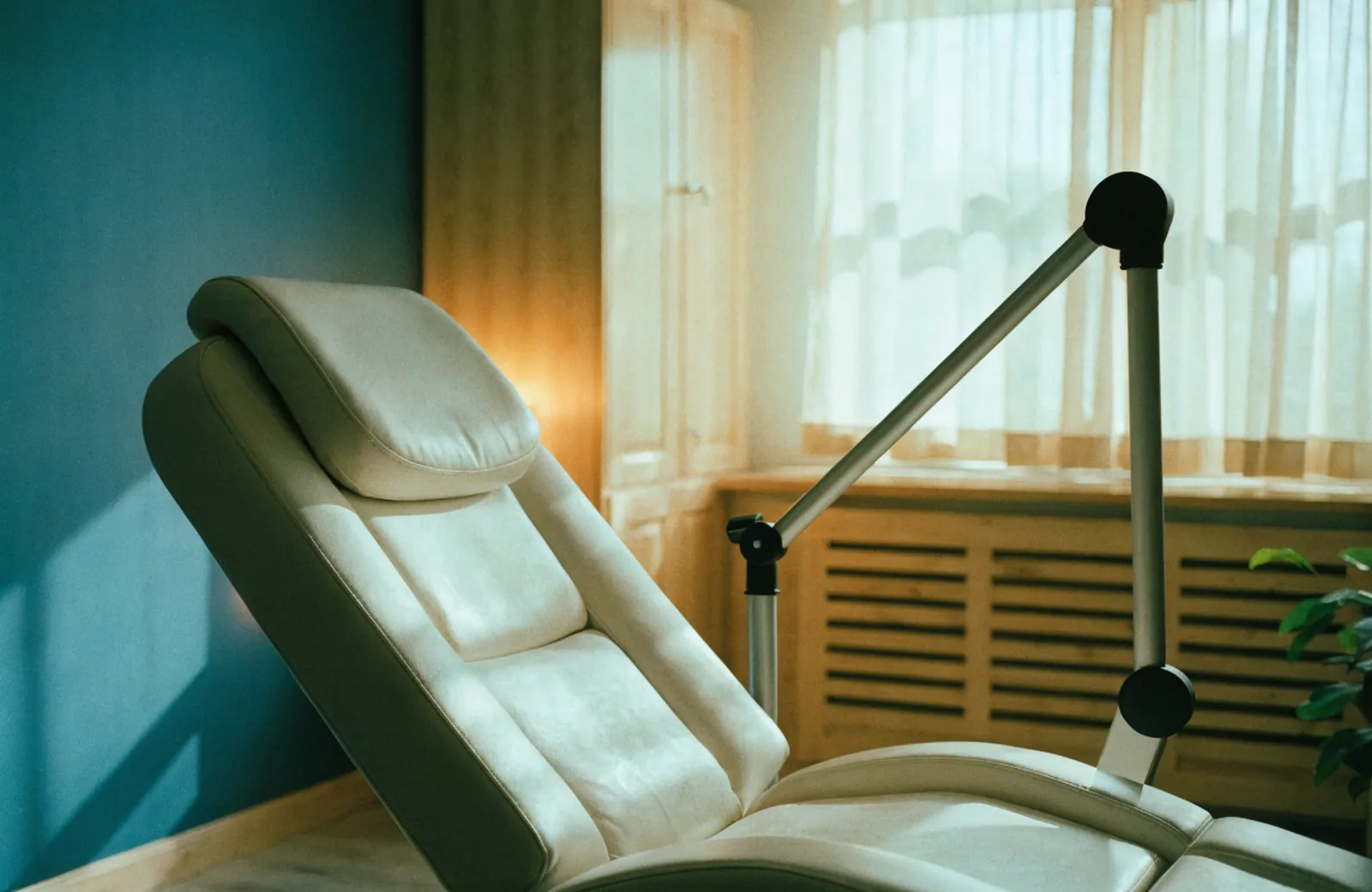 A calm treatment room with a reclining chair beside a sunlit window